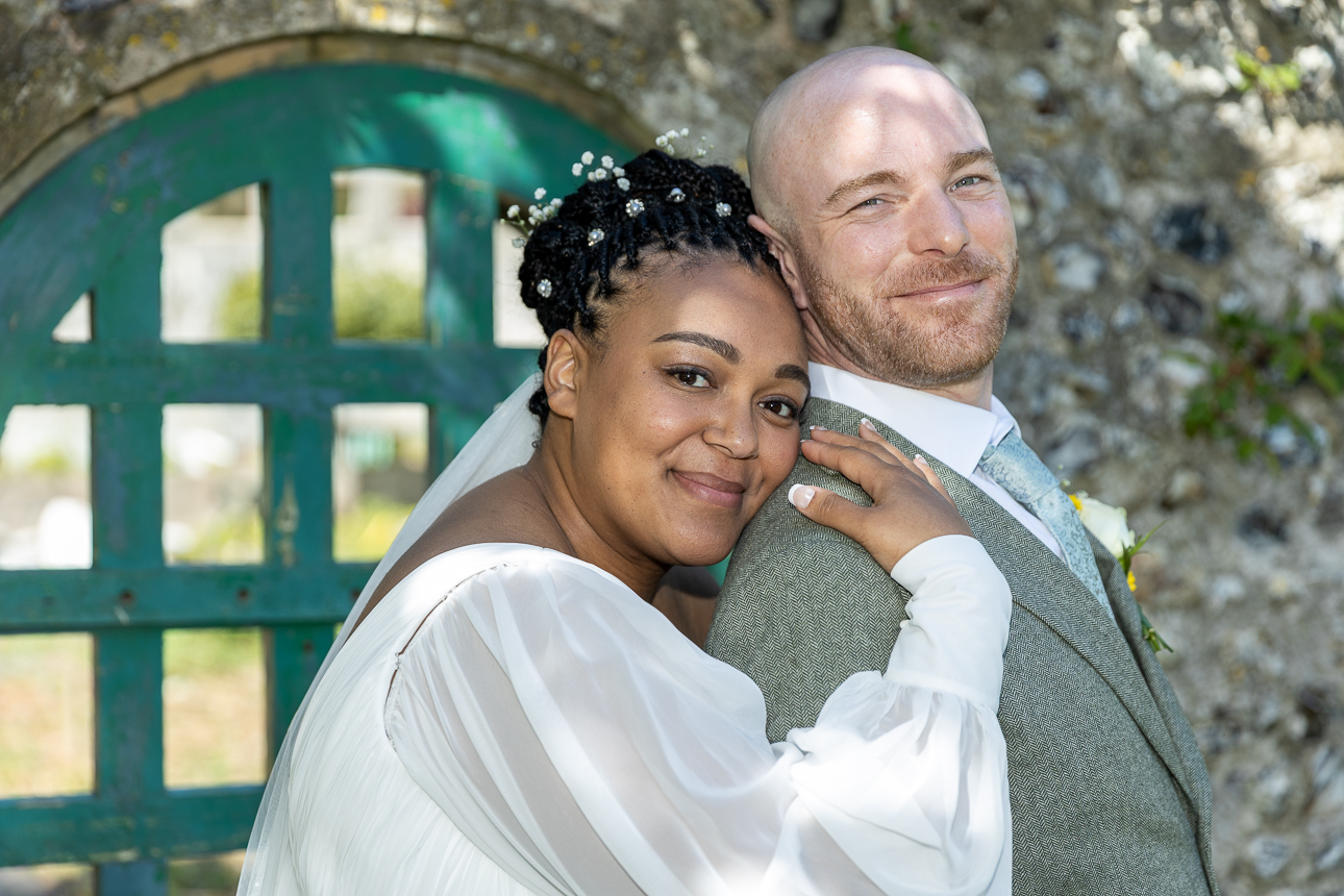 Bride rests her head on groom's shoulder smiling at camera